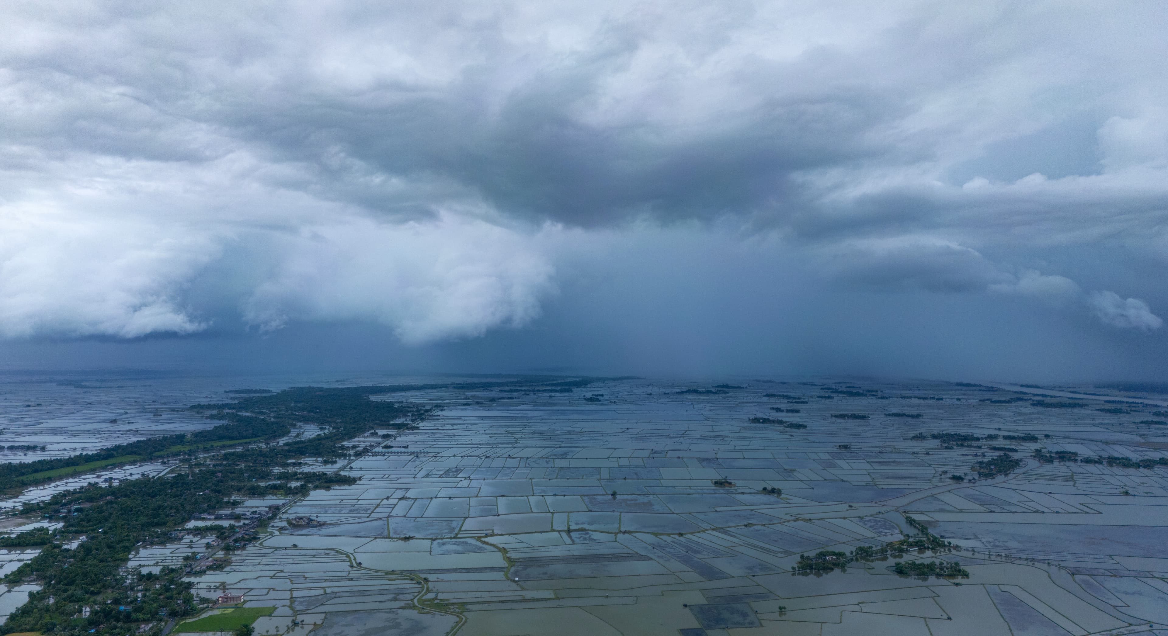Dark pre-monsoon evening storm clouds gathering over green agricultural fields in eastern India before a Kalbaisakhi downpour
